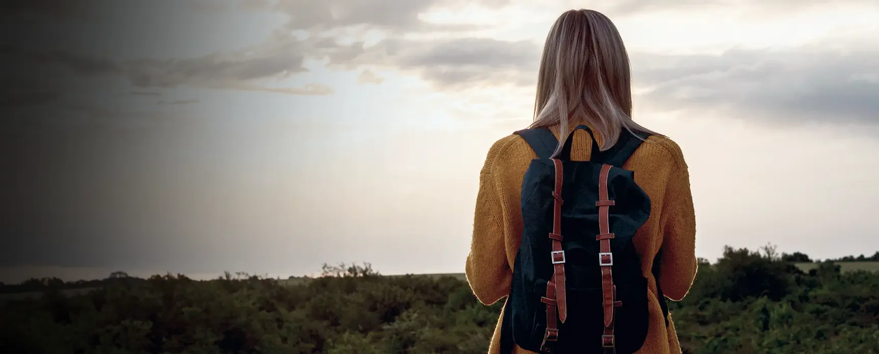 A woman with a backpack looking out over the landscape.