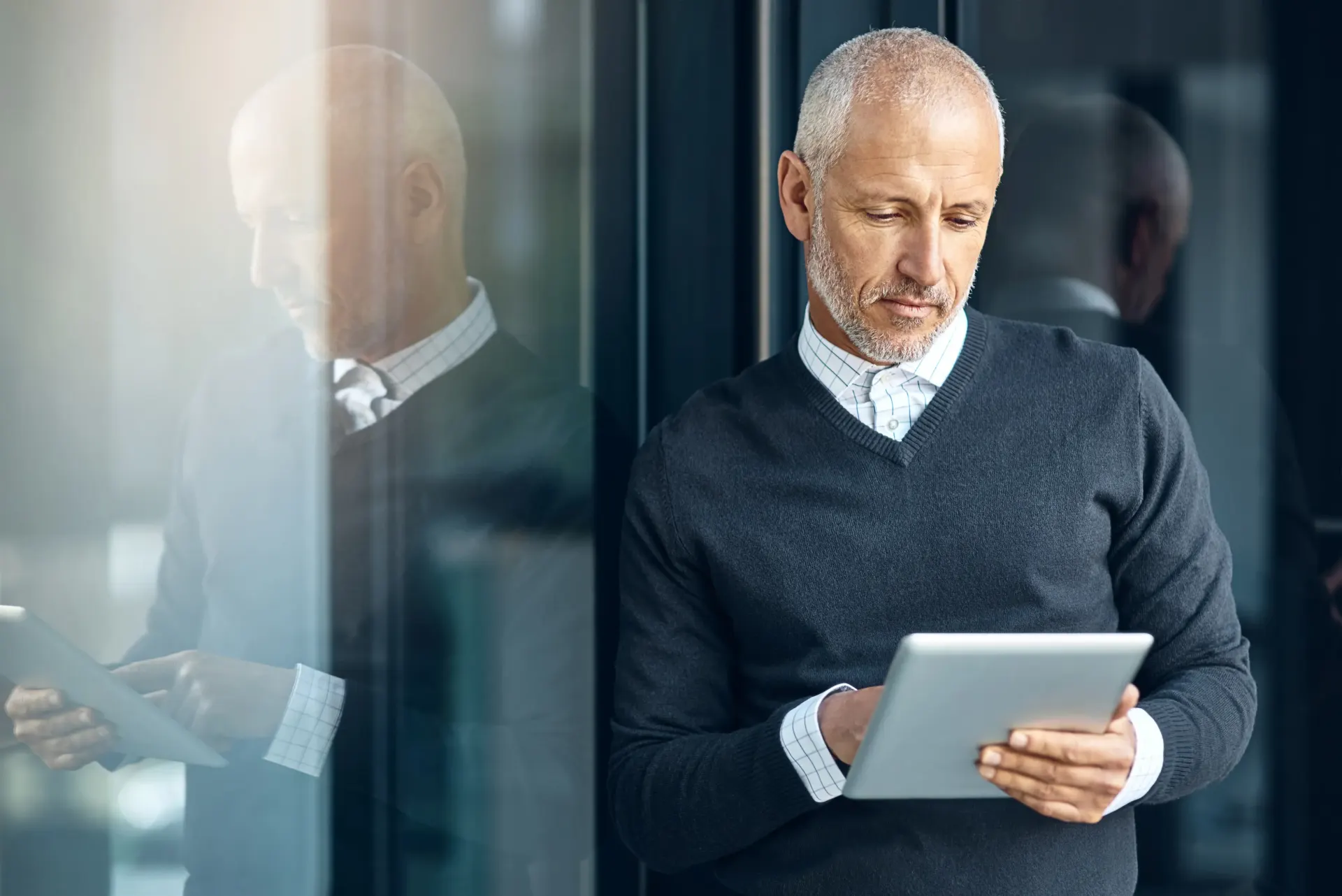 Male healthcare practitioner looking at tablet.