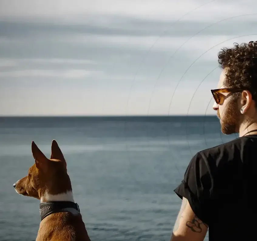 A man and his dog looking out over the sea.