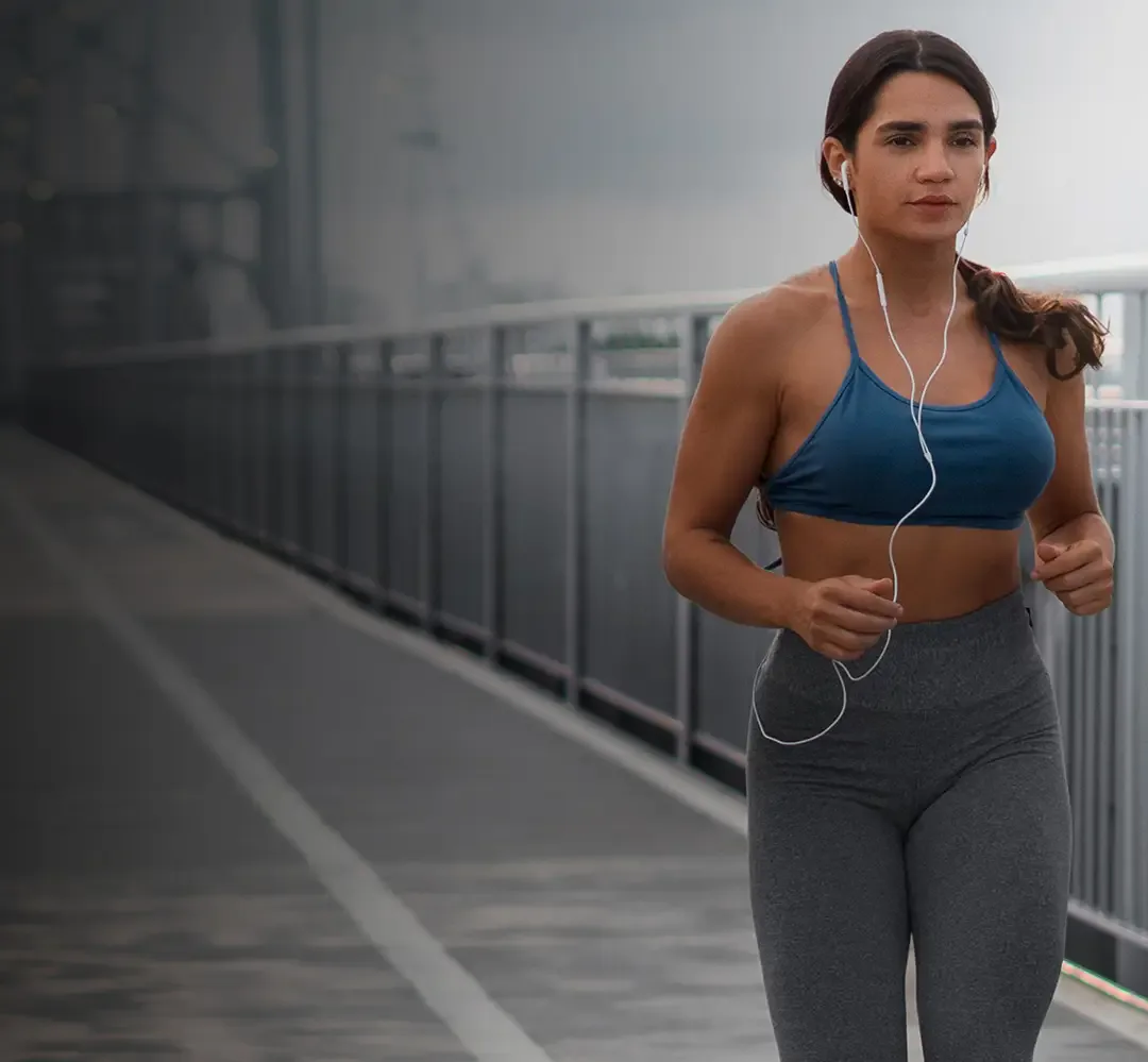 A woman jogging across a bridge.