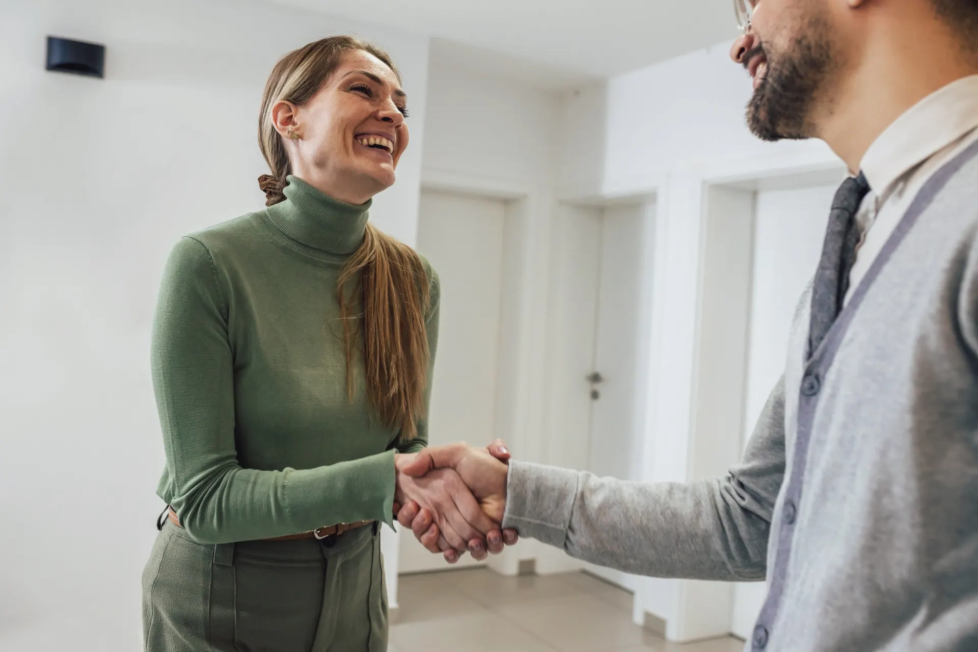 A smiling woman shaking hands with her provider.