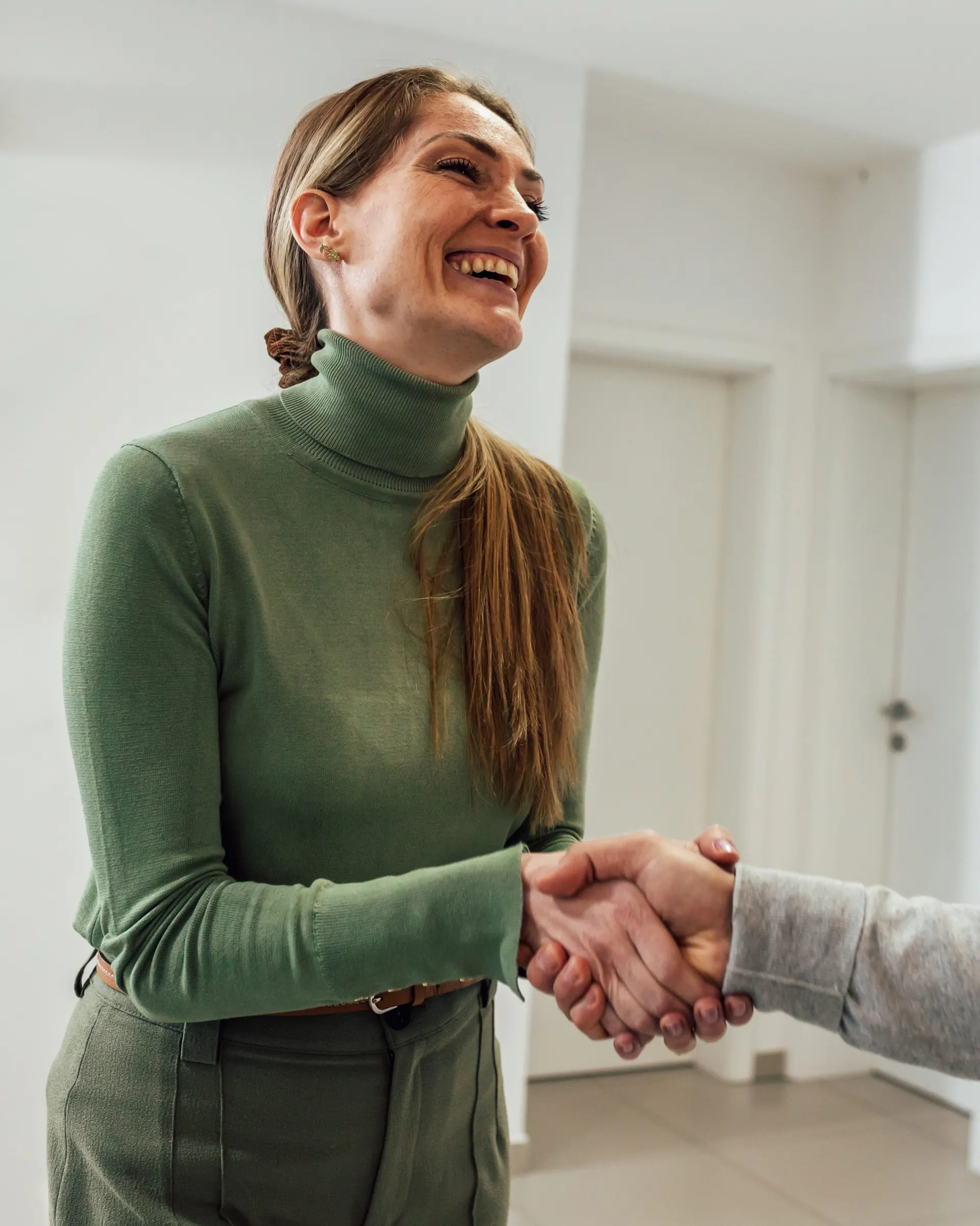 A smiling patient shaking hands with her provider.